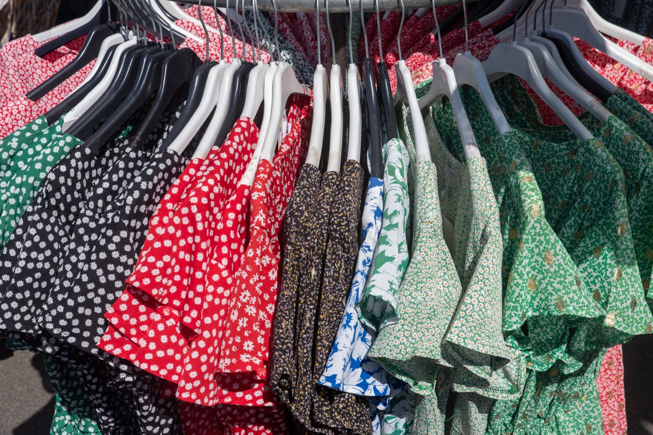 Vibrant collection of floral and patterned dresses hanging on a clothing rack, showcasing diverse styles.