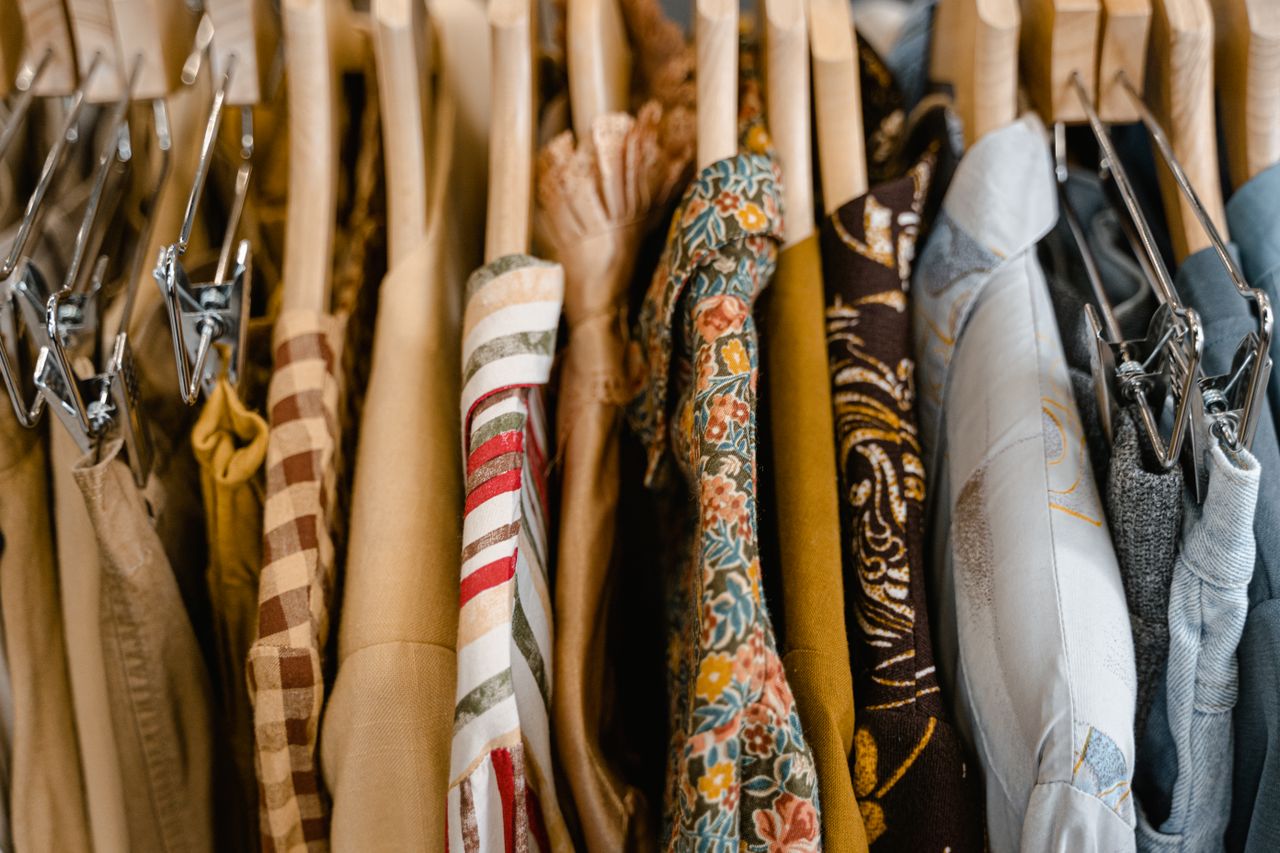 A variety of colorful clothes neatly hung on wooden hangers in a store setting.